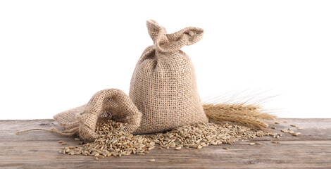 Rye grains, spikelets and burlap bags on wooden table against white background