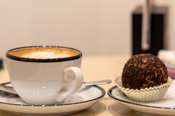 A white coffee mug decorated with a heart-shaped milk foam pattern. The mug sits on a saucer against a yellow background. A minimalist composition, perfect for coffee-related themes, relaxation, 