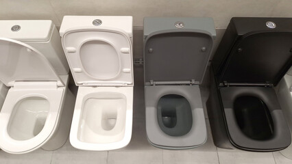 Variety of modern toilet designs in white gray and black shades displayed in bathroom showroom