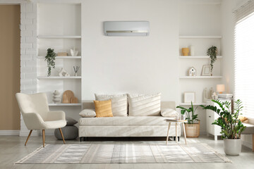 Contemporary furniture, houseplants and decor in living room. Air conditioner keeping comfortable temperature indoors