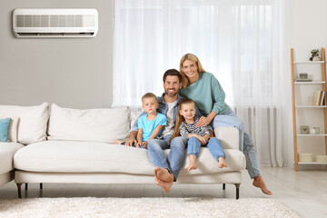 Happy family with children on sofa at home. Air conditioner keeping comfortable temperature in room