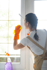 Woman in rubber gloves and apron manually washes window balcony of house with rag cleaner and mop inside interior. Restoring order and cleanliness in spring, cleaning servise