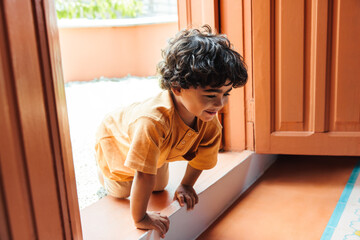 Curious young boy exploring the outdoors while playing near a colorful home © (JLco) Julia Amaral