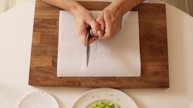 In this close-up video, a woman skillfully shaves garlic with a knife, preparing the ingredient for a delicious meal. Watch her techniques and enjoy the culinary prep - Powered by Adobe