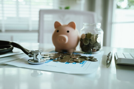 A stethoscope with coins, jar, and piggy bank represents saving money, healthcare costs, insurance, investment, financial planning, and economic security.