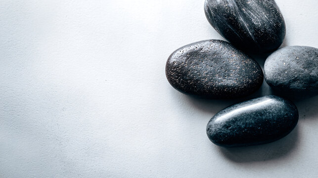 Smooth black pebbles on plain white surface
