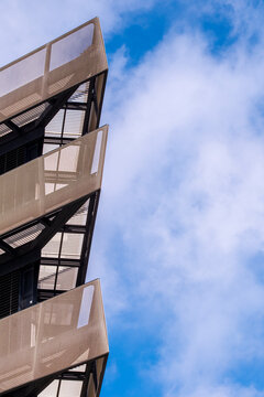Angular modern building edge with steel and glass facade pointing into clear sky and copy space, architectural perspective showing minimalist design, abstract geometry and urban structure fo