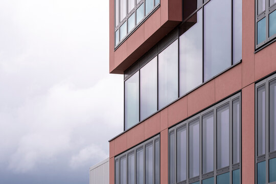 Contemporary red concrete and glass facade detail against sky with copy space, geometric minimalist architecture forming abstract urban composition, architectural perspective for creative ba