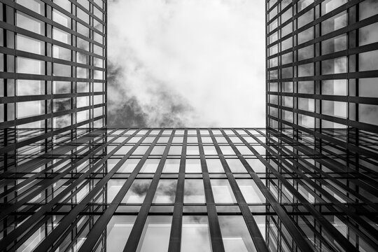 Black and white modern towers with glass facades framing open sky and copy space, minimalist geometry and abstract urban design detail forming strong architectural composition for editorial 