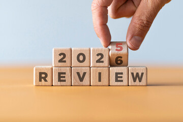 Hand flipping of 2025 to 2026 on wooden blocks. 2025 business and customer review for business strategic planning in the next year 2026. End of the year business concept.