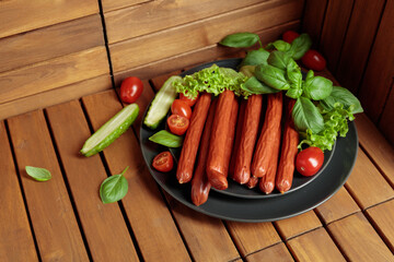 Thin smoked Polish sausages on a black plate.