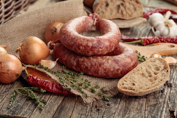 Dry-cured sausage with bread and spices on a old wooden table.
