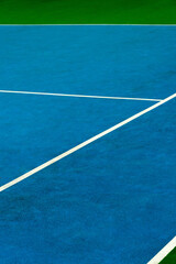 Bright colored tennis court at midday with textured surface and crisp white lines
