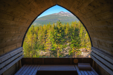 Interior of a wooden sauna in Norway with a scenic view of forest and mountains.