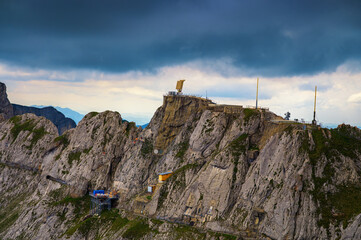 Military radar station with antenna and fencing built on top of a rugged mountain.