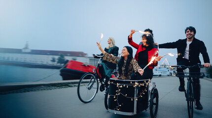Friends enjoying a festive bike ride by the harbor at nightfall