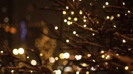 Festive christmas tree branches covered in snow, adorned with twinkling fairy lights, create a magical atmosphere against a backdrop of blurred city lights at night - Powered by Adobe