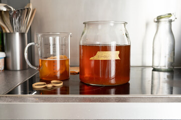 Fermenting kombucha jar and glass mug on modern kitchen counter