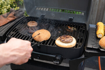 Grilling burgers and corn on outdoor barbecue grill during summer cookout