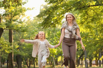 Fototapeta premium Little girl with her mother running in park on autumn day