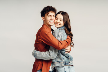 Naklejka premium Young Couple Sharing a Tender Hug with Closed Eyes on Plain Background
