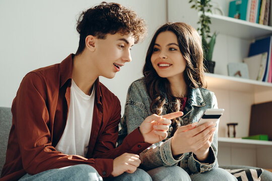 Young couple using smartphone and credit card for online shopping at home