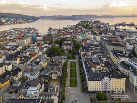 Aerial view of the city's urban layout, where buildings meet the waterfront, creating a tapestry of textures and colors under a serene sky, Bergen, Vestland, Norway.