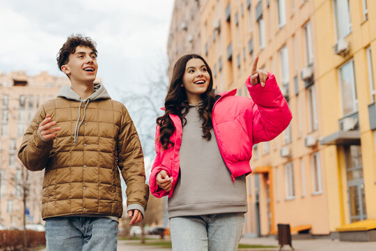 Young couple walking and pointing while sightseeing in the city during winter - Powered by Adobe