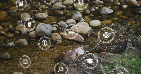 Fototapeta premium Shallow water flowing over smooth stones in woodland creek, with digital overlay icons