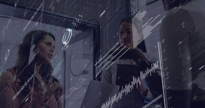 Reading charts on transparent screen, women executives using laptop and tablet in conference room - Powered by Adobe