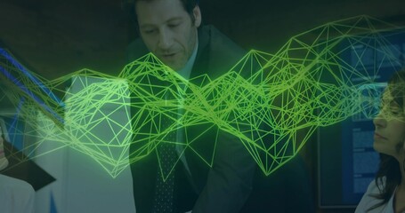 Presenter in suit explaining data leaning on table in meeting room with green network graph overlay