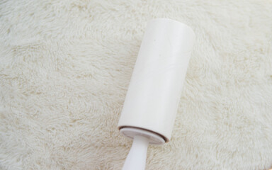 Obraz premium A woman's hand cleans the white soft surface of the furniture with a sticky roller. Cleaning of upholstered furniture from dust, wool and hair.
