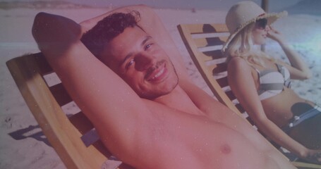 Fototapeta premium Couple reclining on beach loungers at sand dunes, wearing swimwear and straw sun hat