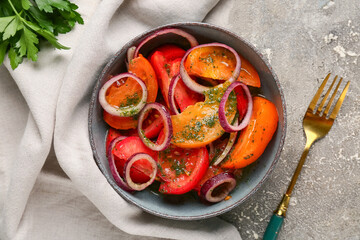 Bowl of fresh tomato salad with red onion and parsley on grey background