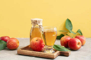 Bottle and glass of fresh apple cider with fruits on grey table