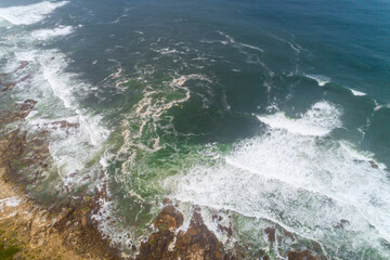 Aerial view of a turbulent green sea crashing against a rocky coast The Raw Power of Nature