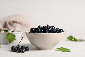 Bowl with fresh black currants on white background