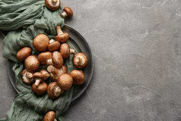 Plate with fresh raw mushrooms on grey background