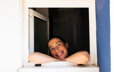 Woman smiling and relaxing in shower looking out window