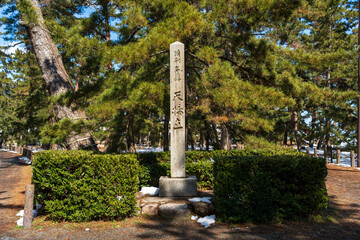 A stone monument of Amanohashidate, designated as a Special Place of Scenic Beauty, stands among snow-covered pine trees in the national park in Miyazu, Kyoto, Japan.