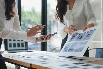 Web designers comparing website mockups on smartphone and printout
