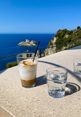 А glass of cold coffee with ice cream in a restaurant with beautiful sea view in Paleokastritsa, Corfu, Greece.