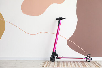 Modern electric scooter near color wall