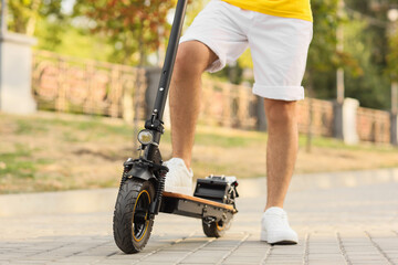 Obraz premium Young man with electric scooter on city street