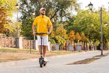 Fototapeta premium Handsome young man riding electric scooter at city street