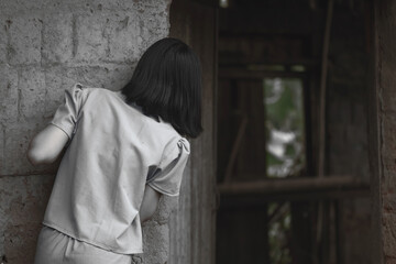 Fear young teenage girl is peeking out of dark old room. Human trafficking concept.black and white image, Rear view
