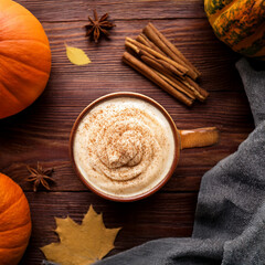 Fototapeta premium Flat lay of pumpkin spice latte with cinnamon sticks, rustic wooden background, copy space, cozy autumn mood