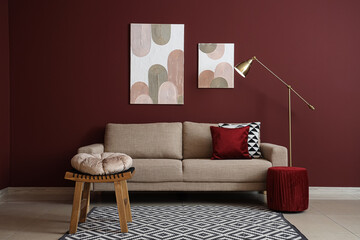 Interior of stylish living room with cozy grey sofa, coffee table and standard lamp near red wall