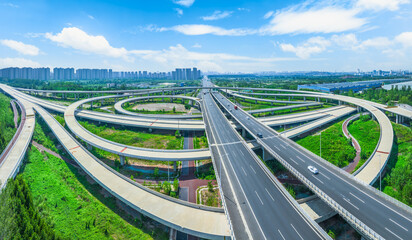 Aerial view of a complex highway interchange with multiple overpasses and curved ramps on a sunny day.
