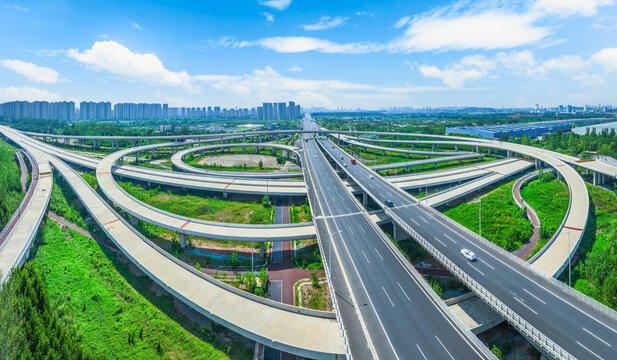 Aerial view of a complex highway interchange with multiple overpasses and curved ramps on a sunny day. - Powered by Adobe